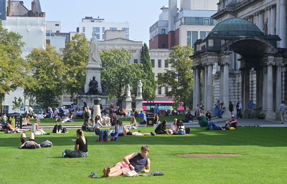 People enjoy the sun outside Belfast City Hall