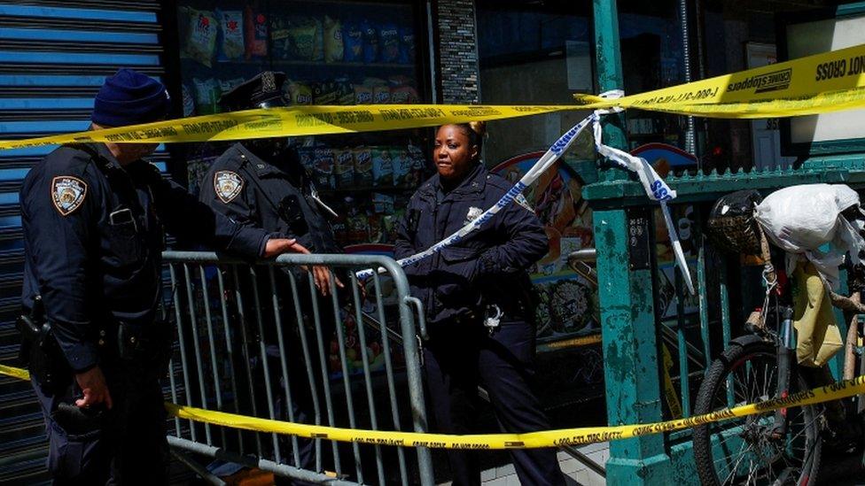 Three officers in uniform stands by the entrance to the subway, which is sealed off with police tape