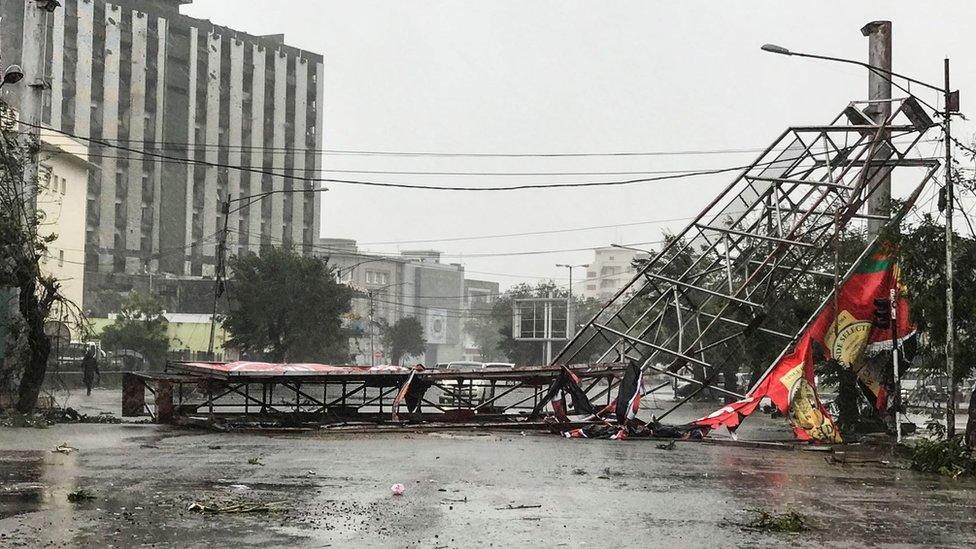 A collapsed advertising hoarding lies in the road