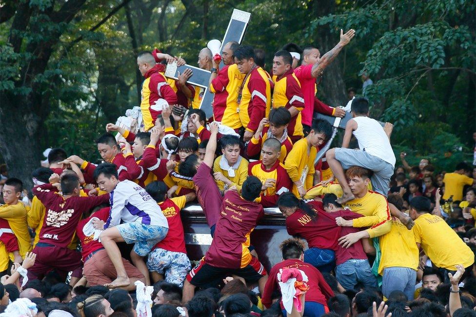 Filipino Roman Catholic devotees climb the carriage to kiss and rub with their towels the image of the Black Nazarene. Manila, Philippines, Monday 9 January 2017.