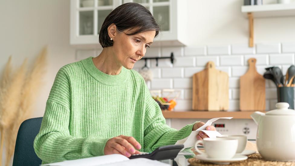 Woman in kitchen with bills