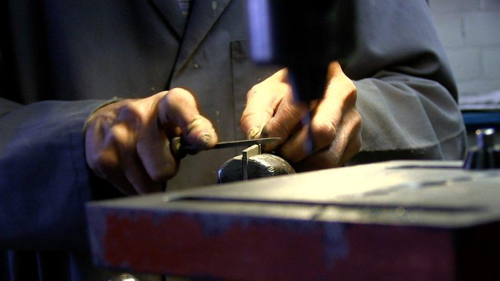 A man uses a file on a piece of metal