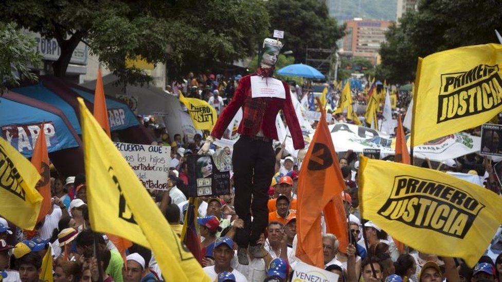 Opposition supporters chant and wave flags as a mannequin representing judge Susana Barreiros, who sentenced Leopoldo Lopez, is paraded around during a rally in Caracas, Venezuela on 19 September, 2015.