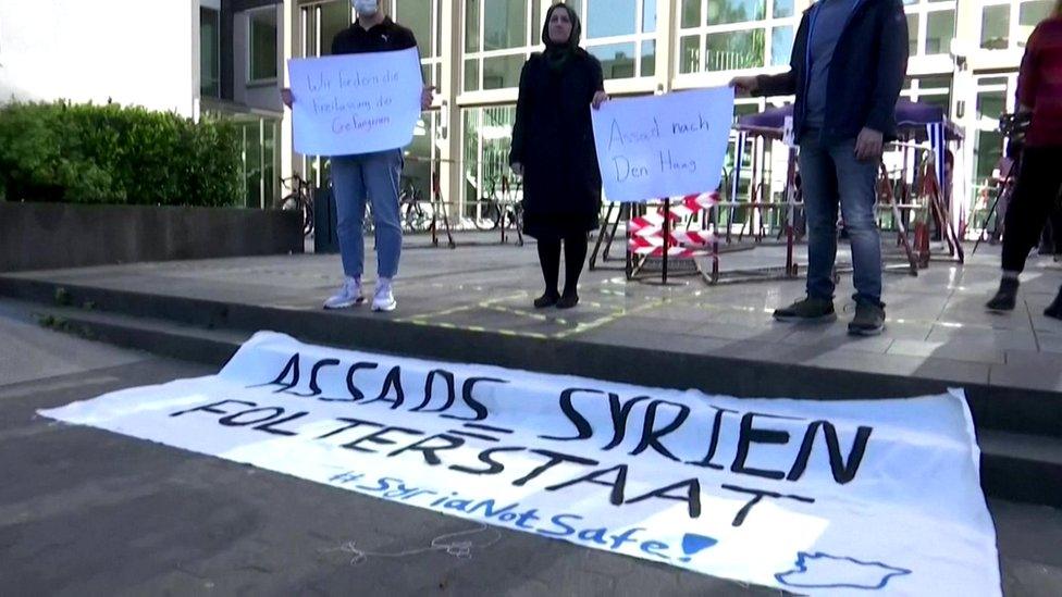 Activists hold a banner outside the court in Koblenz