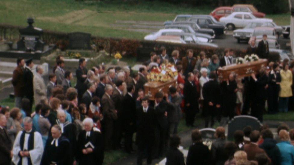 The coffins of the Herron family members are carried into a church as hundreds of mourners watch on