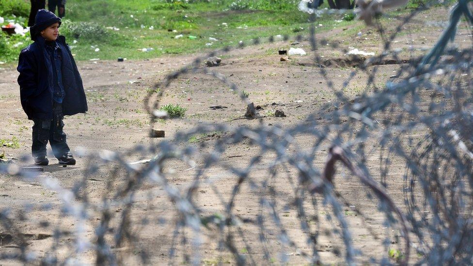 A young migrant boy waits in front of the Hungarian border fence at the Tompa border station transit zone on April 6, 2017