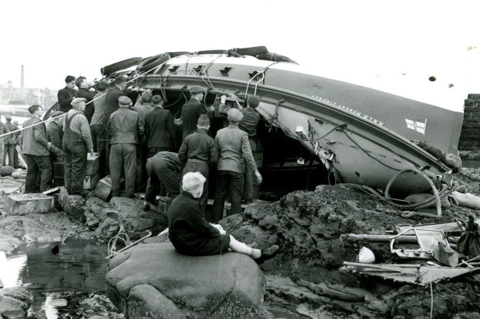 People get together to pull the washed-up lifeboat upright