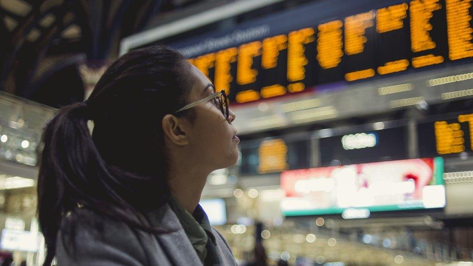 A woman looks at the train timetable at a station