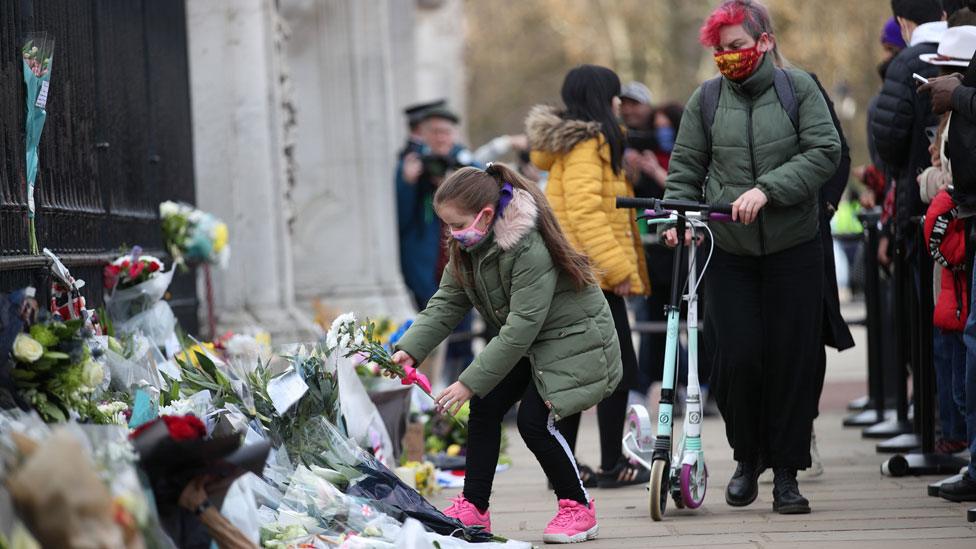 Child places flowers outside Buckingham Palace