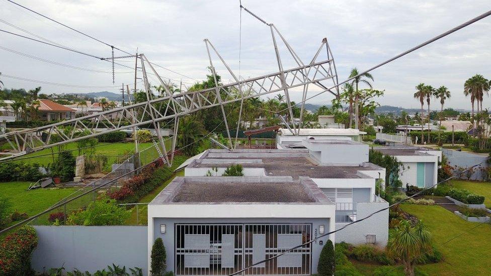 A power line tower downed by the passing of Hurricane Maria lies on top of a house in San Juan, Puerto Rico on November 7, 2017