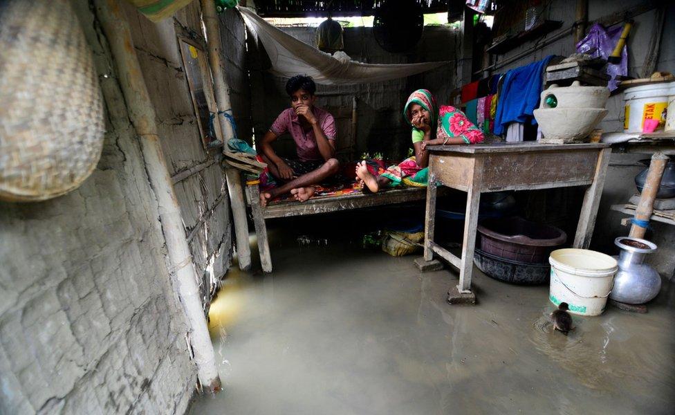 A couple sits on a bed as their home is inundated by flood waters in the flood affected Morigaon district of Assam, India, 12 July 2019