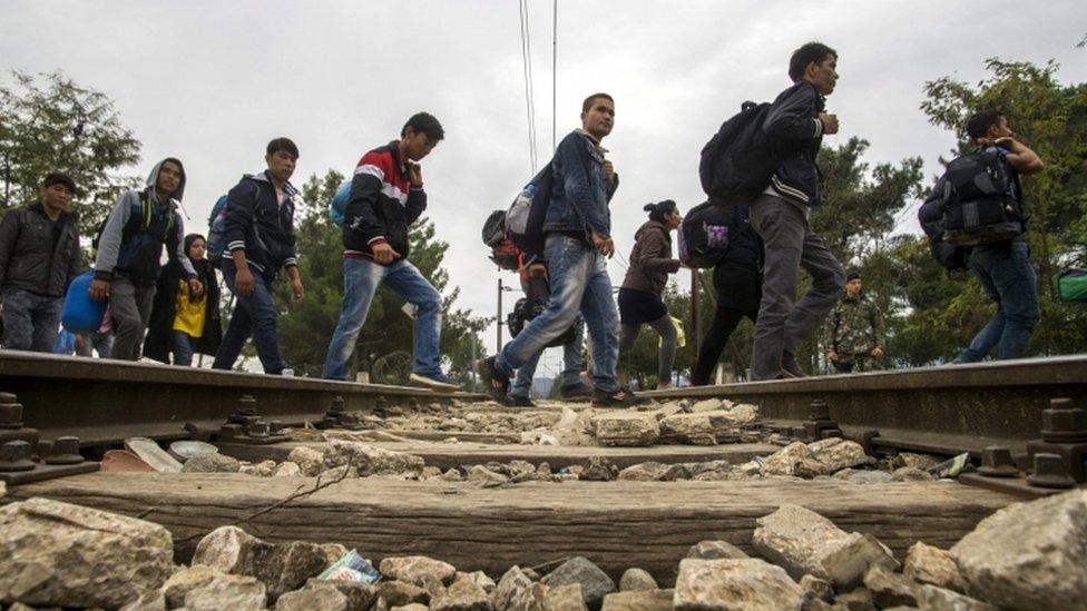 Syrians walk along a rail track