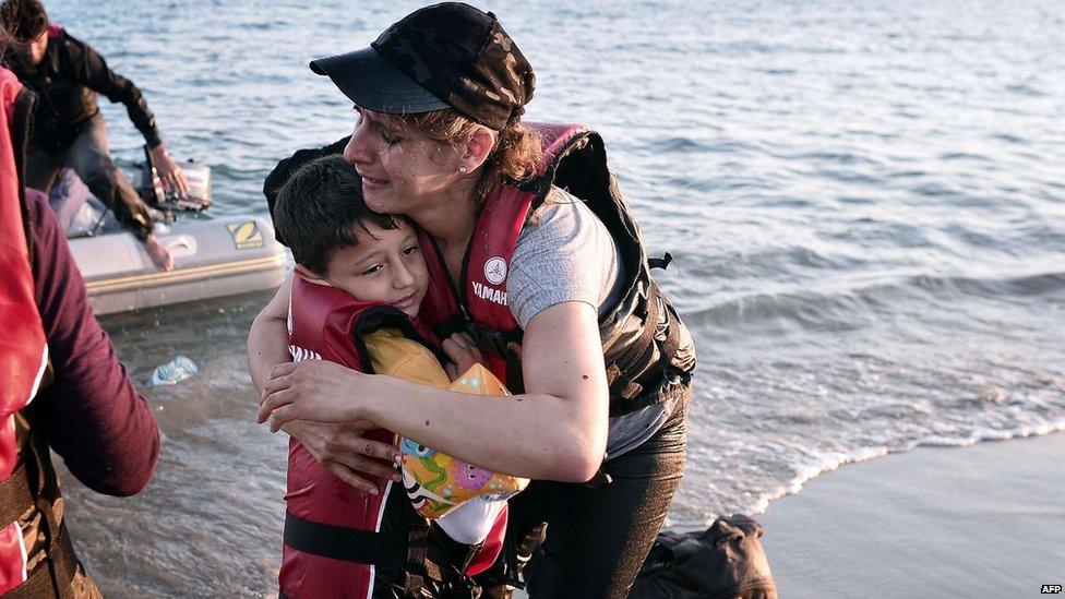 A migrant woman hugs her son after safely arriving to the shores of the Greek island of Kos on 18 August 2015