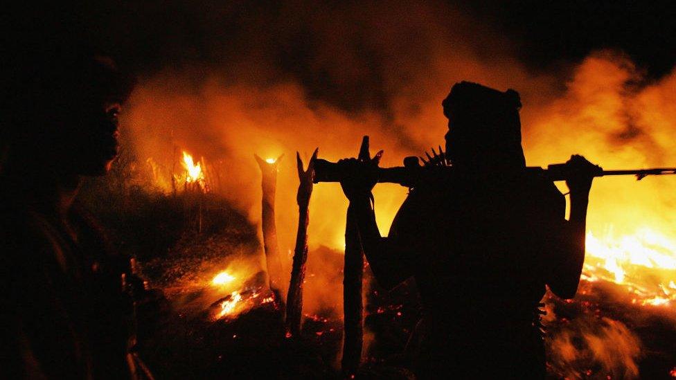 An armed Sudanese rebel from the Justice and Equality Movement (JEM) arrives at the abandoned village of Chero Kasi less than an hour after Janjaweed militiamen set it ablaze