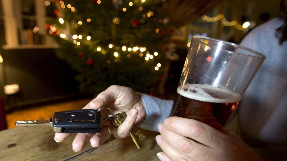 Person in a pub holding pint of beer and car keys