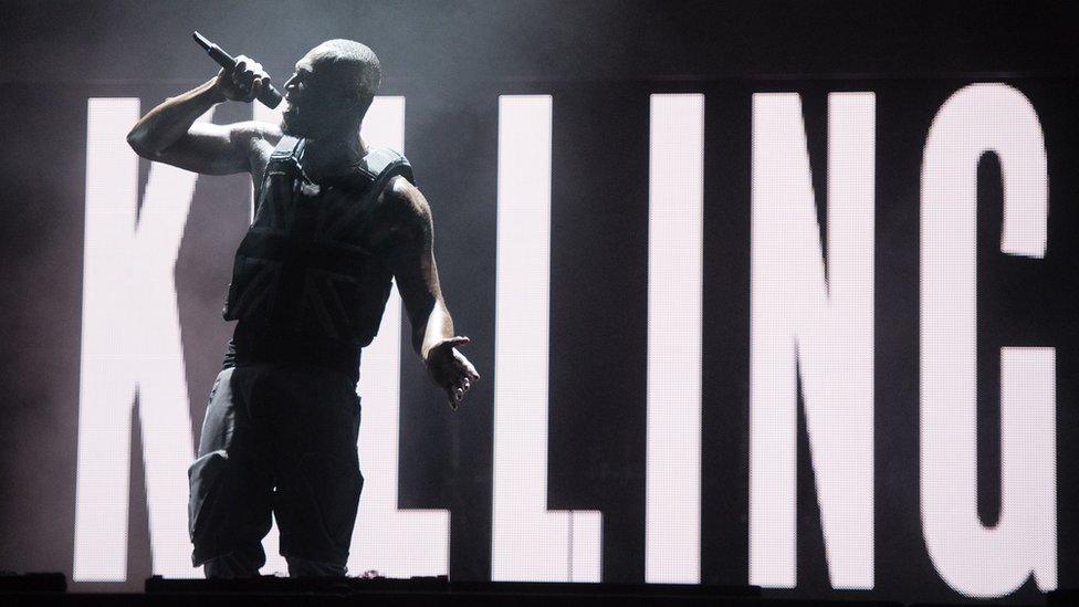 Stormzy in front of a screen that reads "Killing"