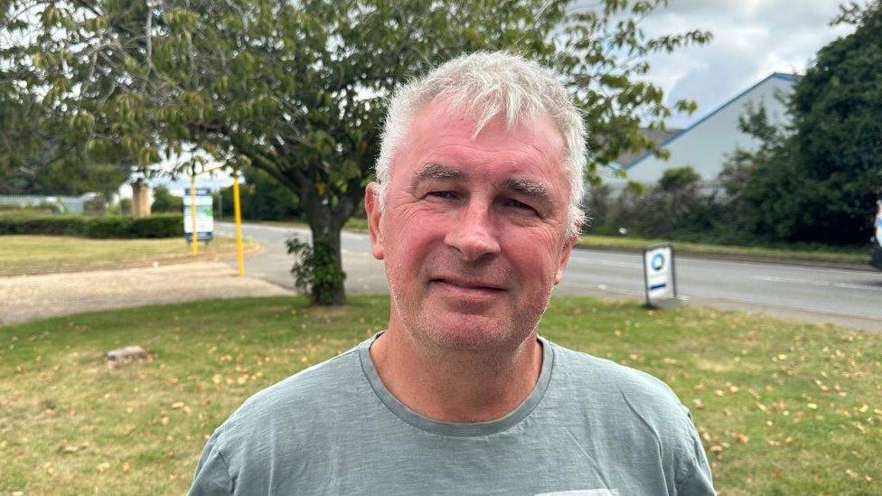 Man in grey top stands outside primary school