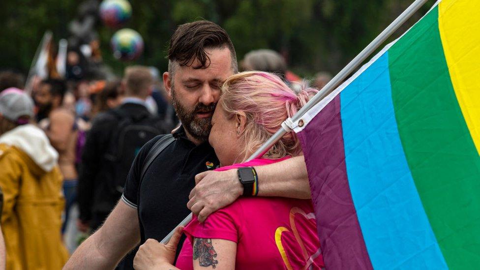 Image shows two protesters embracing