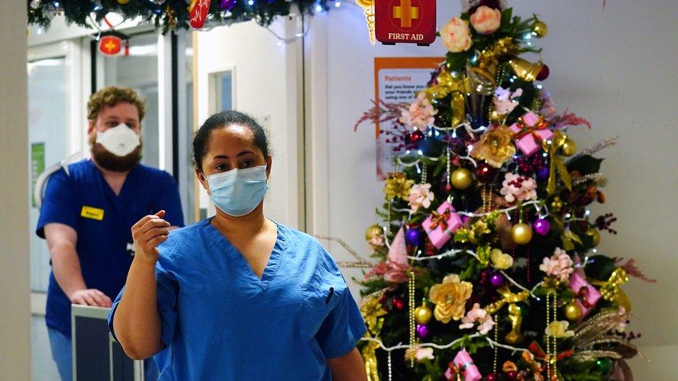 Medical staff walk past a Christmas tree on a ward for Covid patients at King"s College Hospital, in south east London.