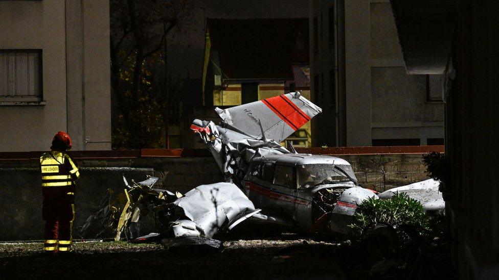 A firefighter stands next to a twin-engine Piper PA-30 Twin Comanche plane after it had to make an emergency landing in Villejuif a Parisian suburb