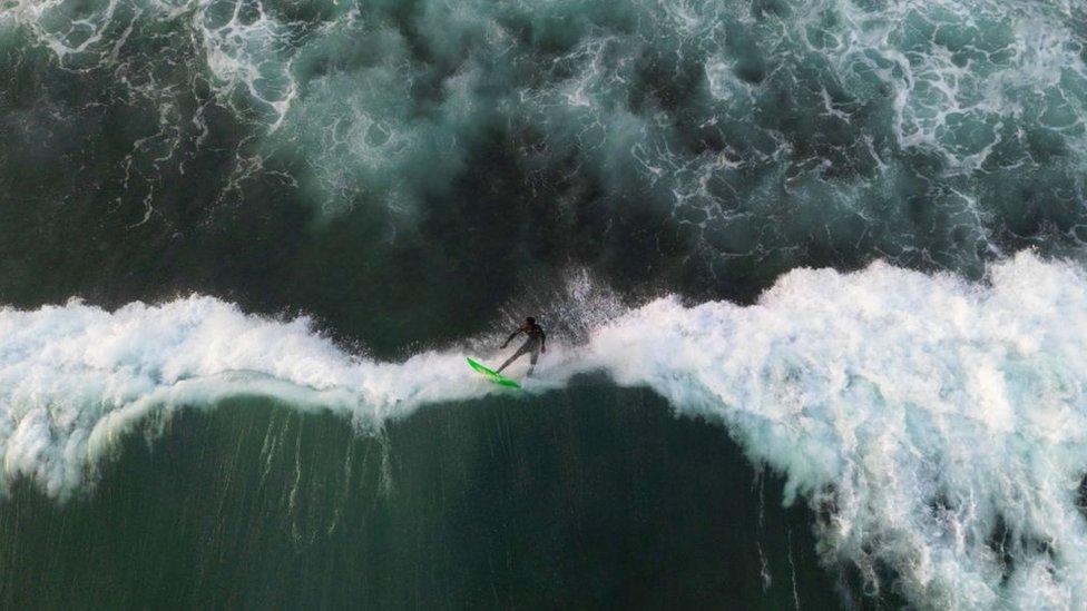 An aerial view of a surfer surfing among the giant waves of Atlantic Ocean in Dakar, Senegal on May 25, 2024. In Senegal, which has 724 kilometres of coastline, surf schools with large and small beaches along the coastline are flooded by surfing enthusiasts. Surfers gather at the beach at noon enjoy the sea until the evening hours as the waves grow.