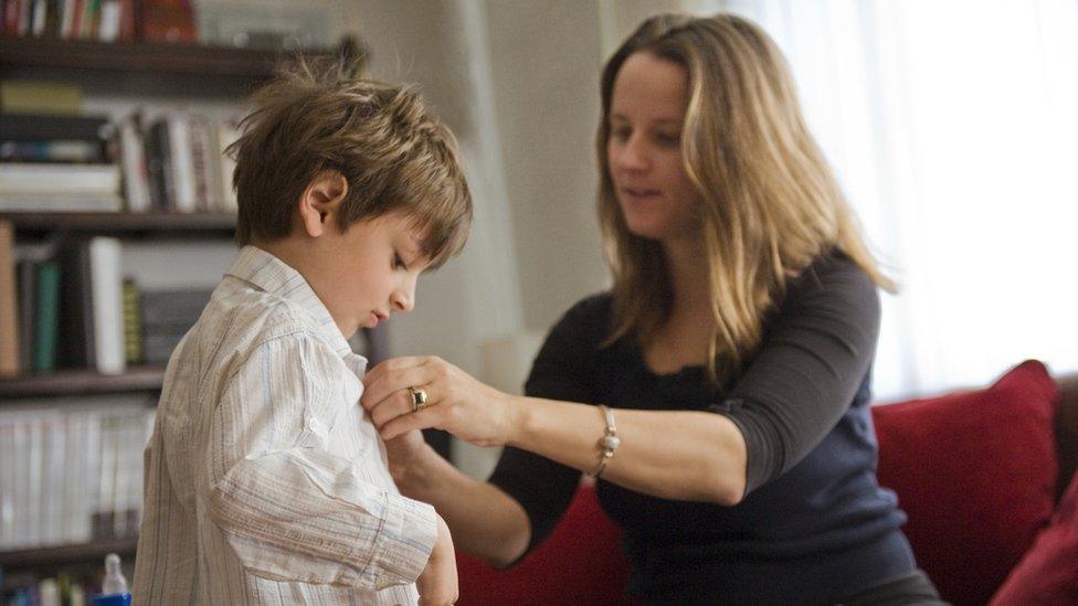 mum-helping-son-put-on-shirt.