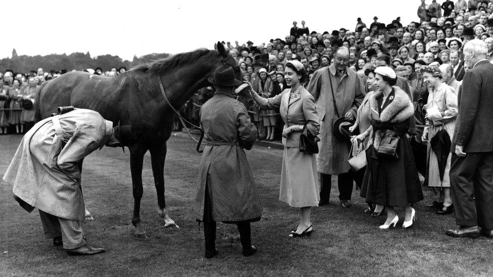 1954 Queen Elizabeth II patting her horse, Aureole after it came in first at the Royal Ascot race meeting on Ascot Heath, Berkshire. Princess Margaret Rose (1930 - 2002) and Queen Elizabeth the Queen mother look on