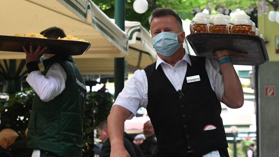 A waiter carries beer glasses at the Schweizerhaus beer garden in Vienna, Austria