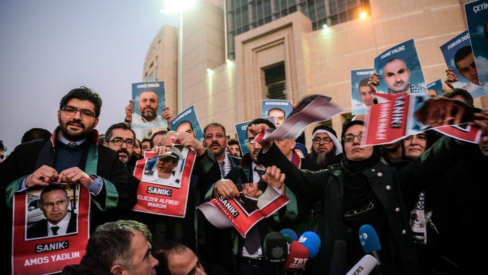 Lawyers tear into pieces pictures of accused ex-Israeli army officers as families (back) hold pictures of victims on 9 December 2016 outside the Istanbul courthouse as Turkish court is expected to rule in the case of Israelis charged in absentia over a deadly commando raid on a Gaza-bound aid ship in 2010.