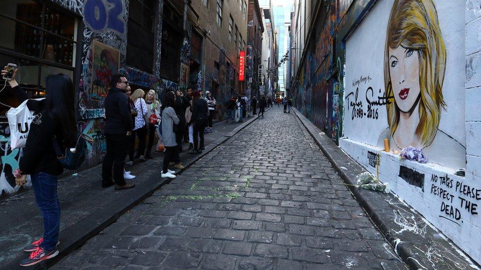 People next to a mural of Taylor Swift