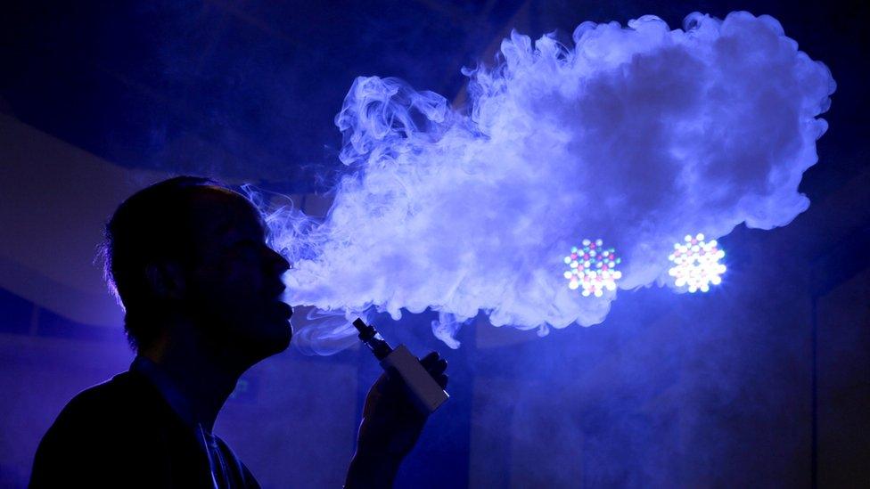 An exhibitor staff member uses a vape at VAPE CHINA EXPO in Beijing