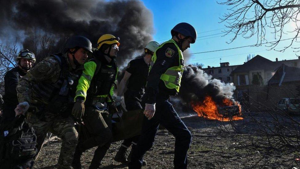 Emergency workers carry an injured woman at a site of a Russian missile strike