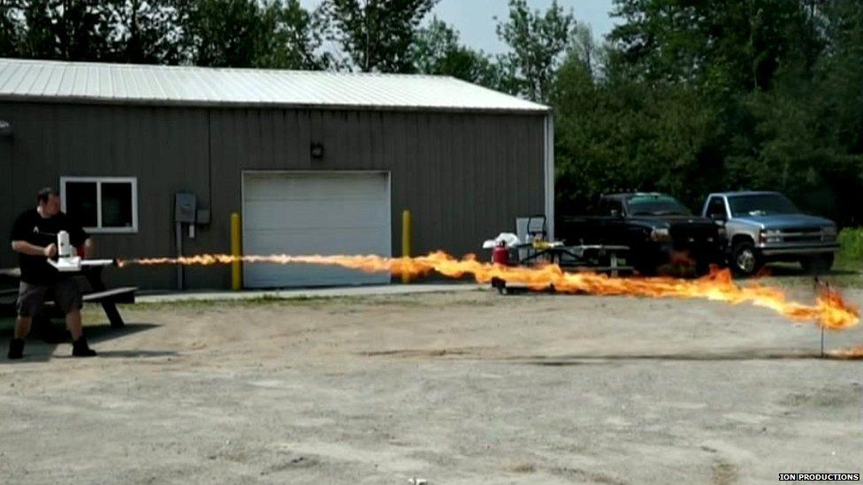 Chris Byars uses his flamethrower for target practice across a car park