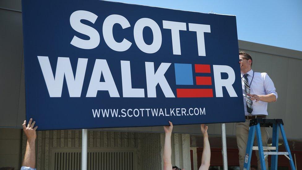 Two men hold up a giant Scott Walker sign.