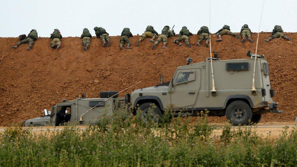 Israeli soldiers lie along an earth barrier along the border with the Gaza strip in the southern Israeli kibbutz of Nahal Oz on March 30, 2018