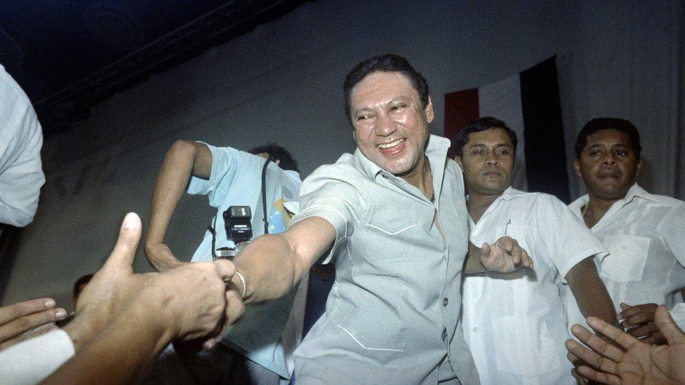 This photo taken on February 12, 1988 in Panama City shows General Manuel Antonio Noriega reaching down to shake hands of followers who attended Noriega's birthday party held by government officials and party workers.