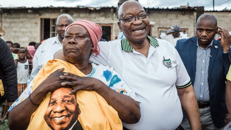 Jacob Zuma (2ndR) is held tightly by ANC supporter Maria Mandweni during a door to door campaign visit in Shakaskraal township, on April 16, 2019