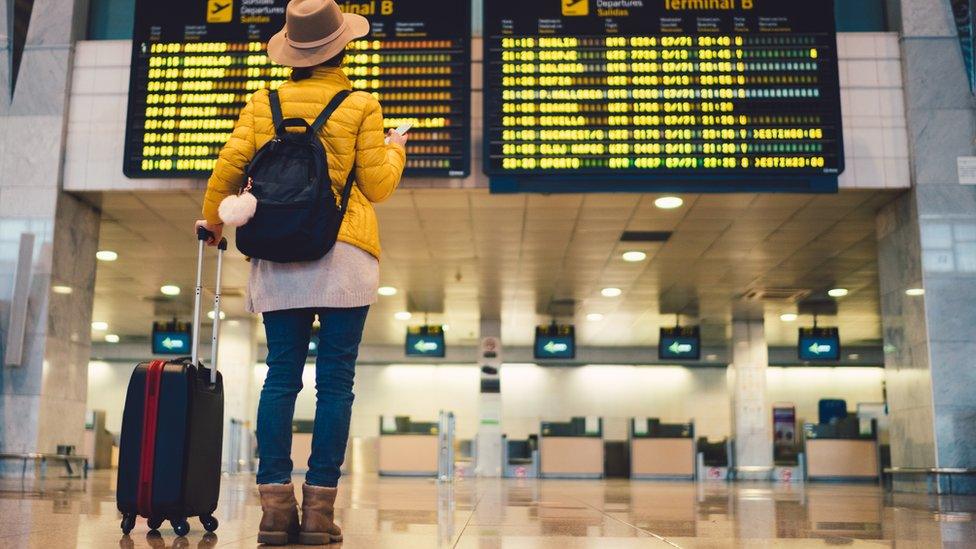 Woman looking at a board with flight details in the airport