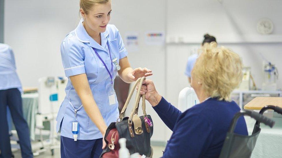 A patient is handed her bag by a nurse