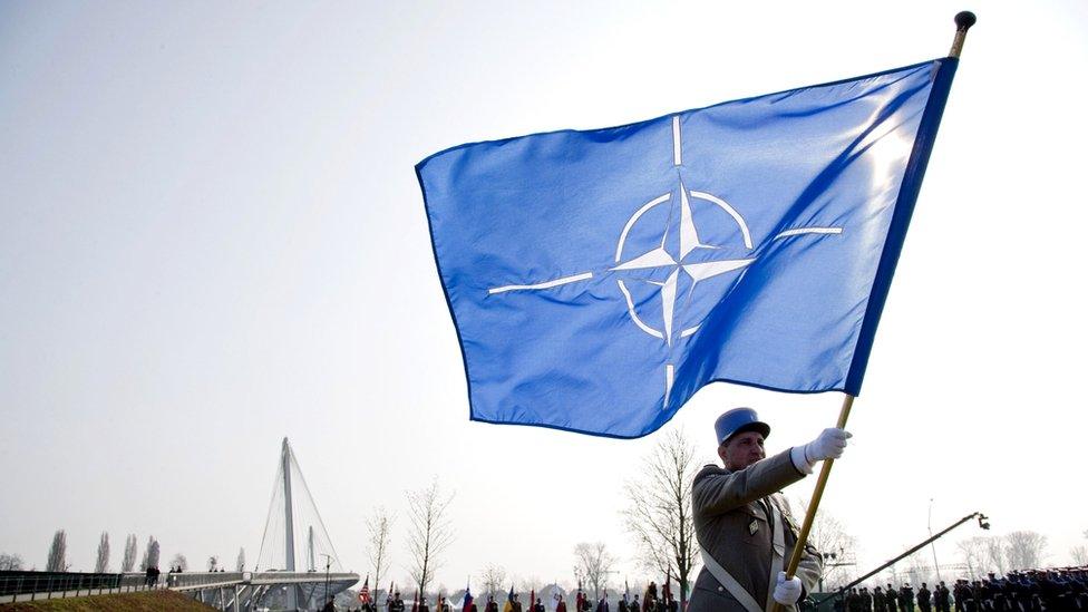 A solider with a Nato flag at a ceremony in Germany