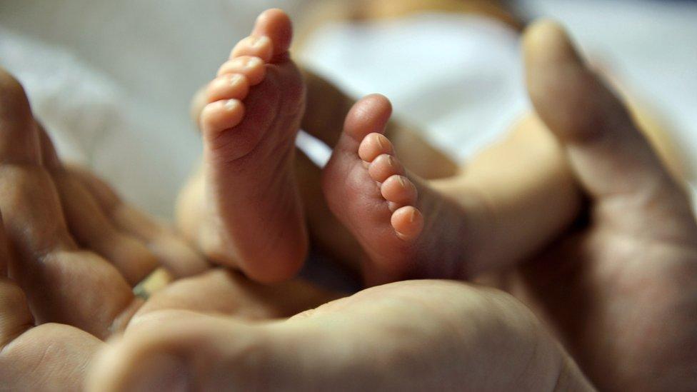 A father cradles the tiny feet of his baby girl