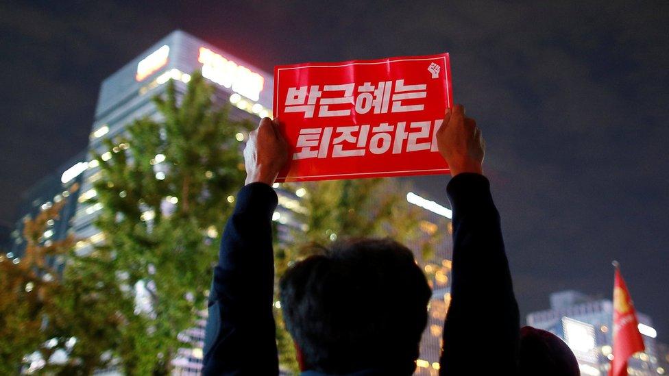 View of a sign being held up to the night sky by a protester in central Seoul, South Korea, 31 October 2016.