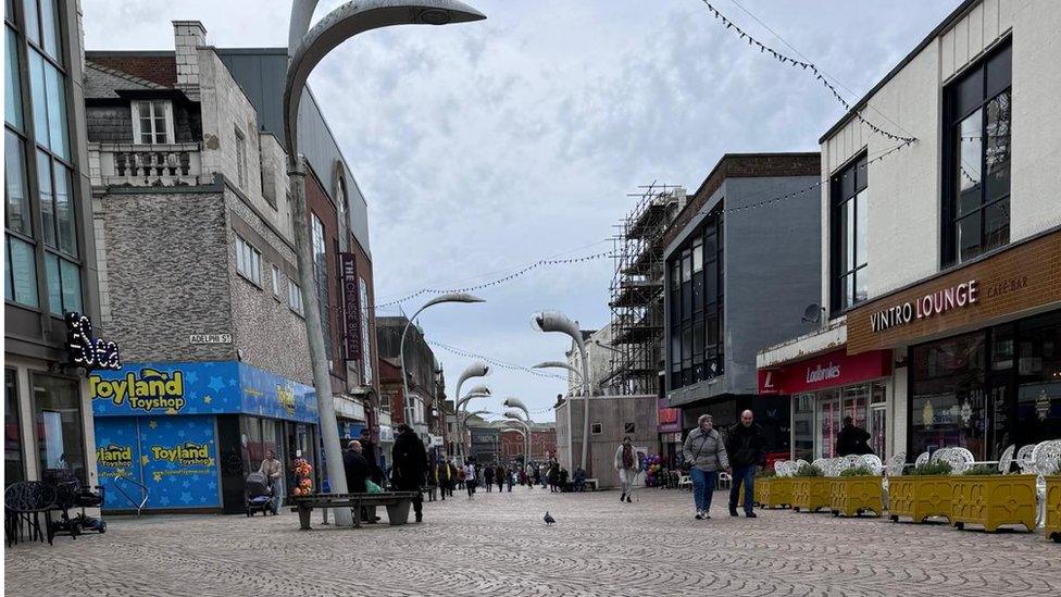 The view from the top of Church St from near the Winter Gardens, showing shops ang cafés.