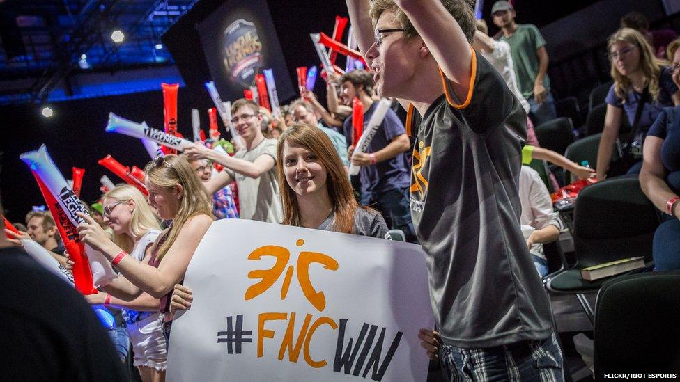 Fans hold up team banners at a League of Legends tournament