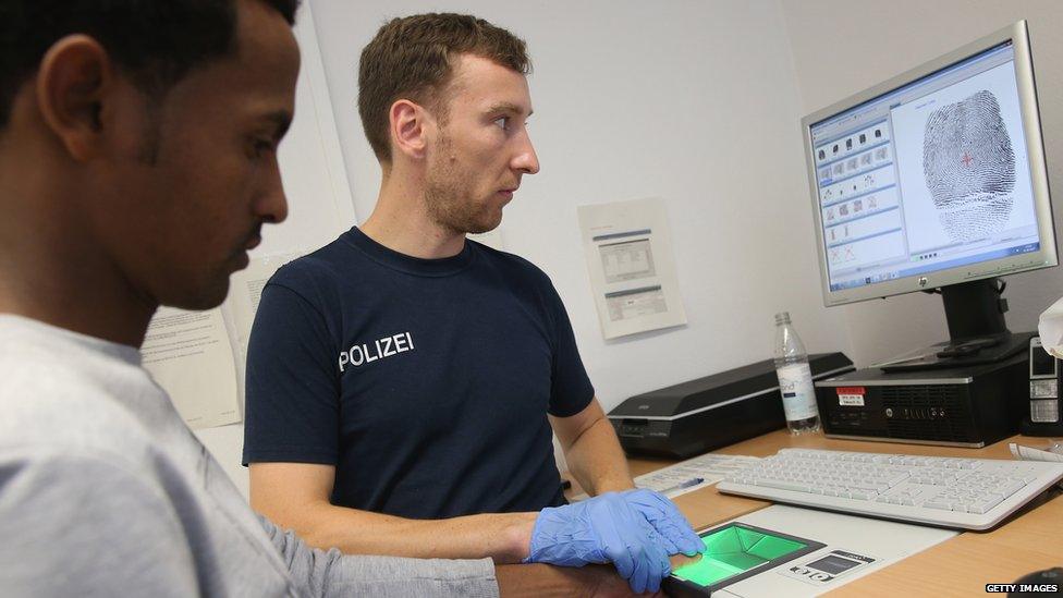 A German policeman measures the height of a newly-arrived migrant from Eritrea as part of the registration process at a center for migrants at a facility of the German Federal Police (Bundespolizei) on August 31, 2015 in Rosenheim, Germany.