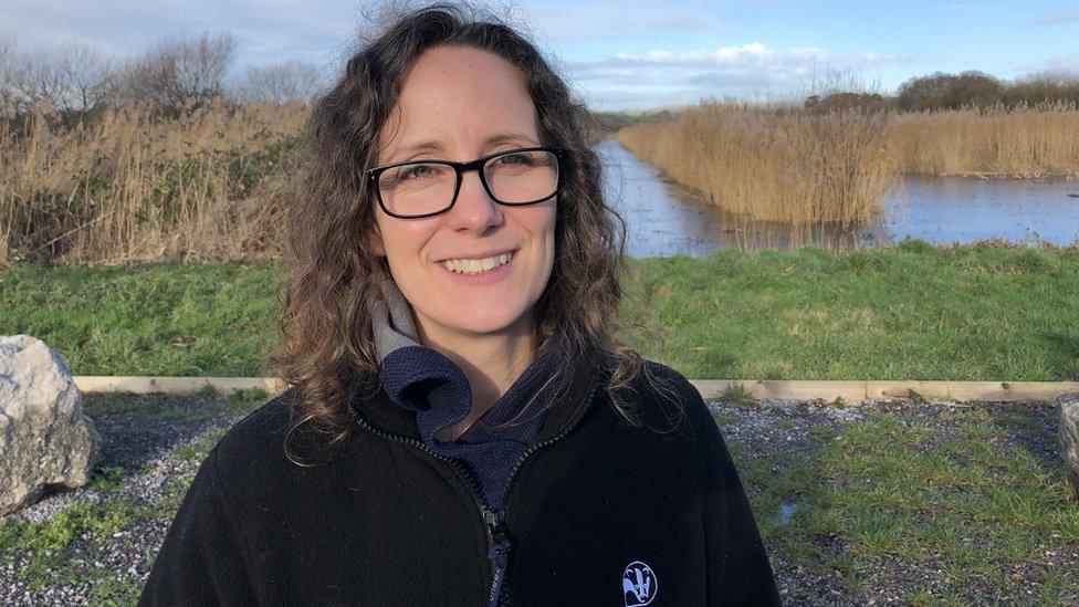 A woman with curly hair and glasses outside