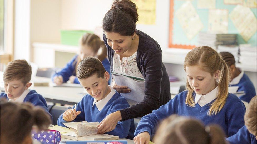 Female teacher with her pupils in classroom - stock photo