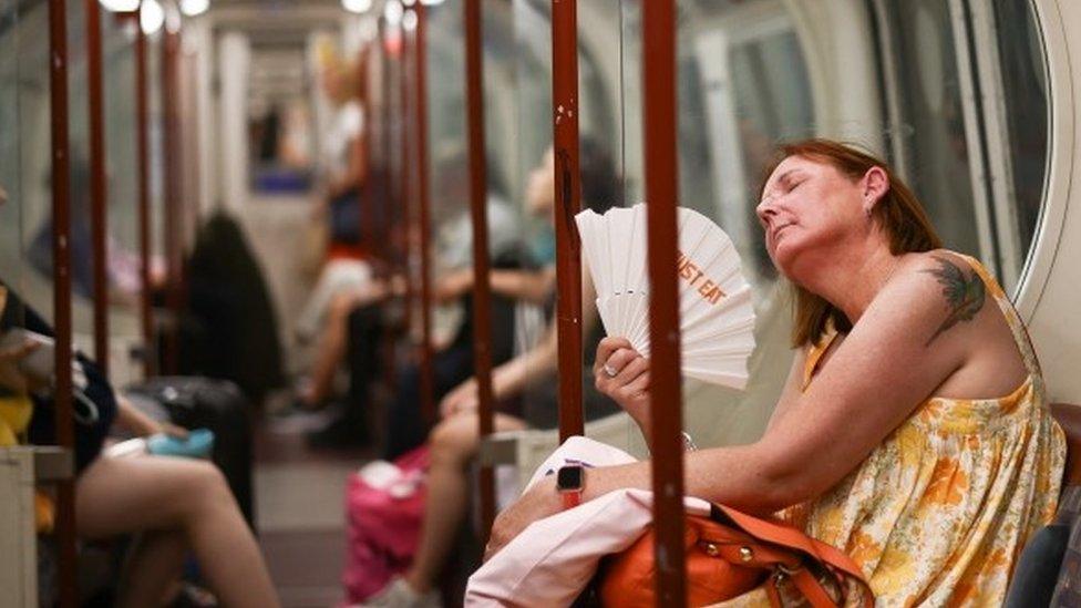 A woman fanning herself on an Underground train