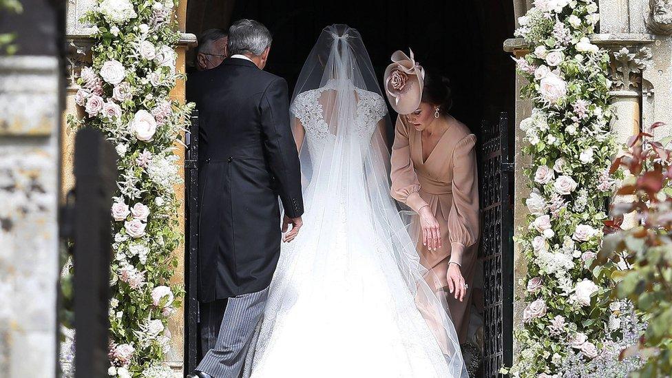 The Duchess of Cambridge arranges the train of her sister Pippa Middleton as she arrives.