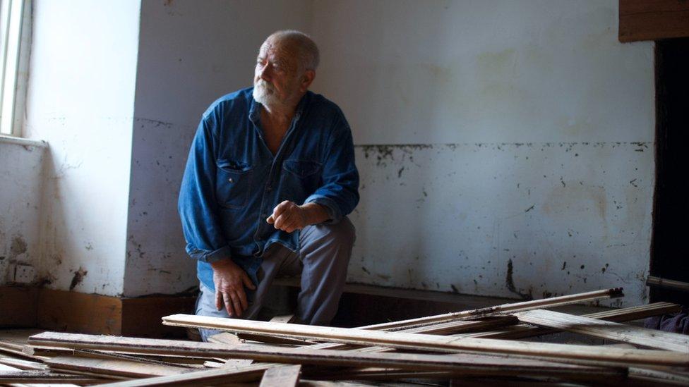 Man in flood-damaged room